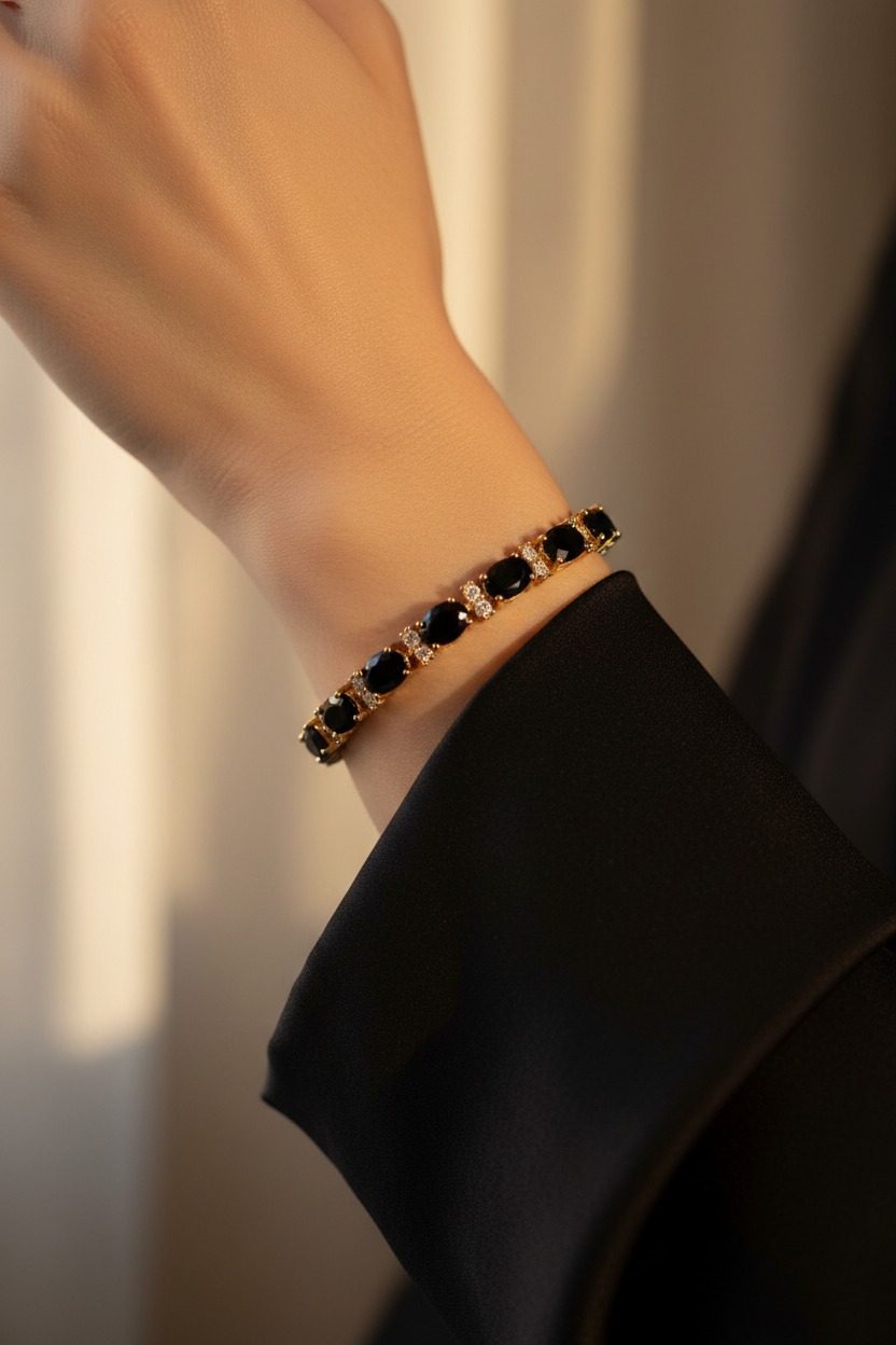 Woman wearing a yellow gold black onyx and created diamond tennis bracelet with a black silk sleeve