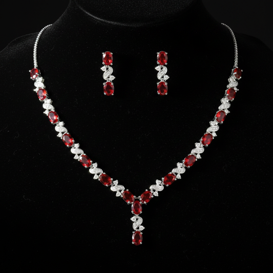 Red ruby and created diamond oval necklace and earrings set flat lay on black velvet
