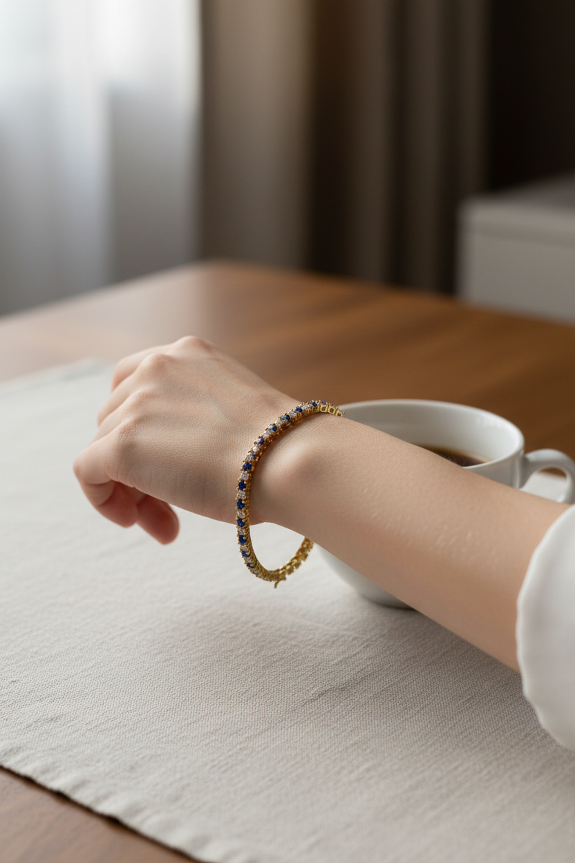 Woman wearing a yellow gold blue sapphire and created diamond tennis bracelet at a table